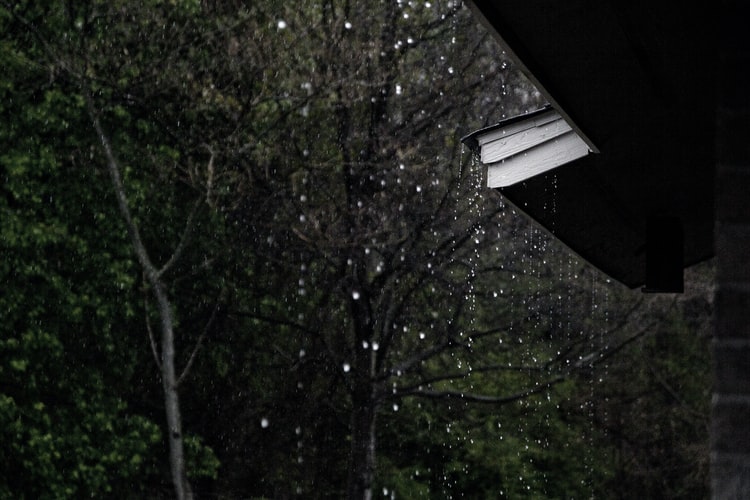 Rain falling from a house roof and gutter.