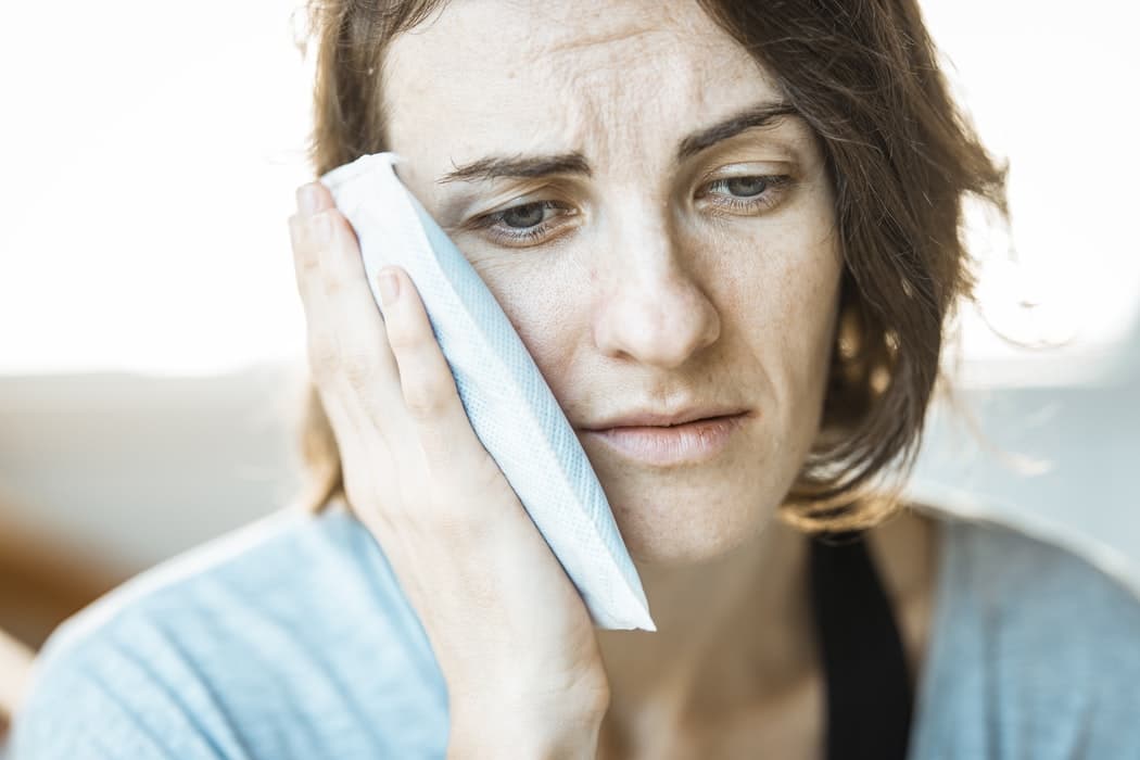 Woman holding an ice pack up to her ear.