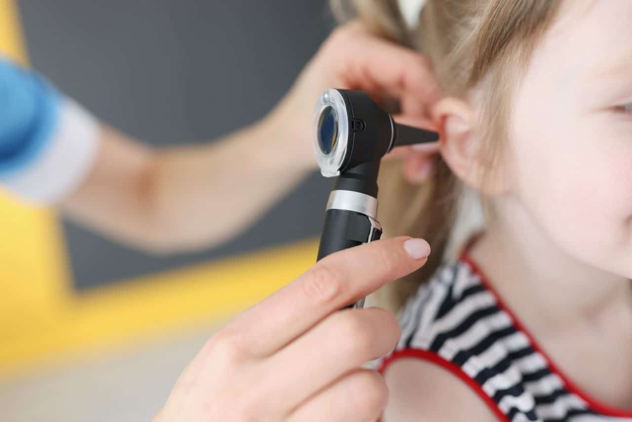 Doctor examines ear of young girl.