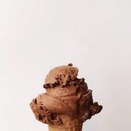 A scoop of chocolate ice cream on a cone.