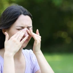 Asian woman scratching itchy eyes in a park