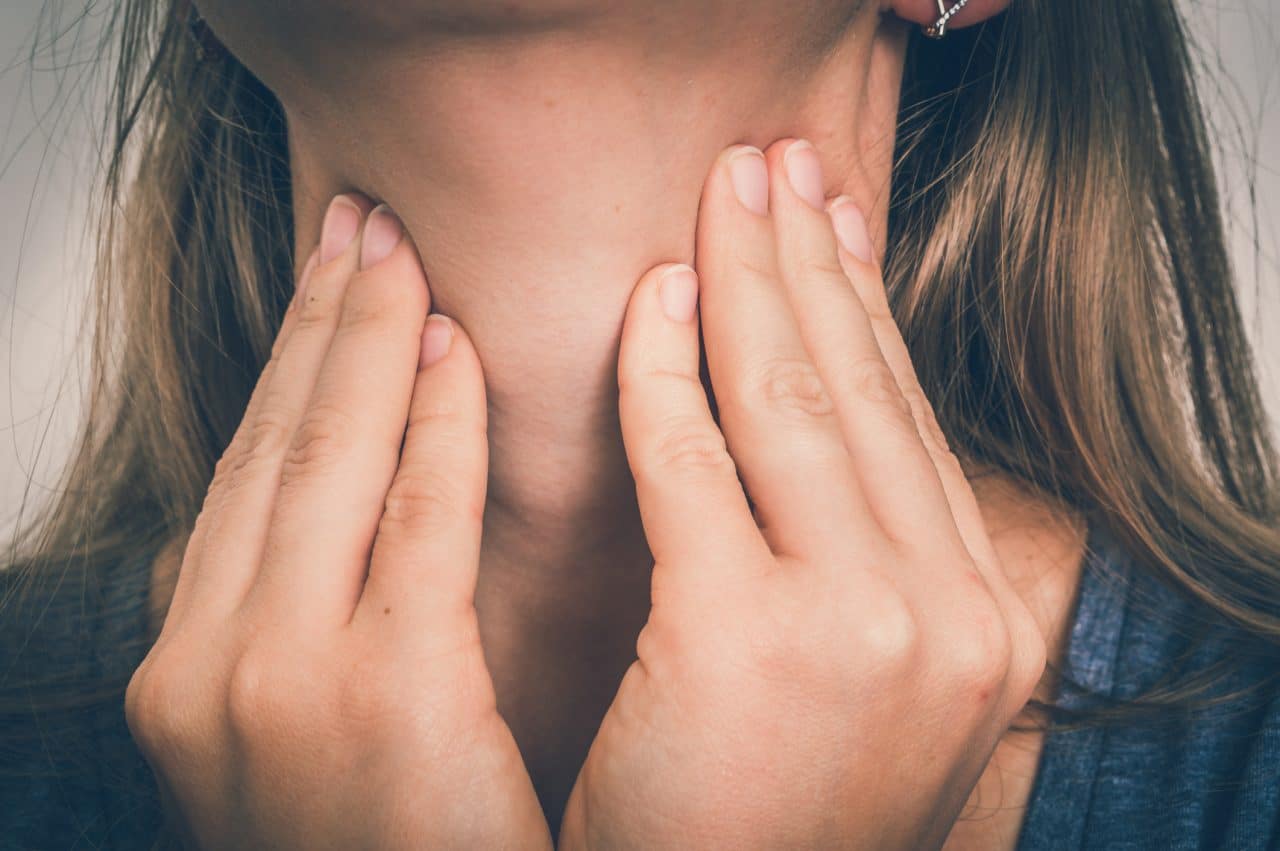 Woman feeling her throat.