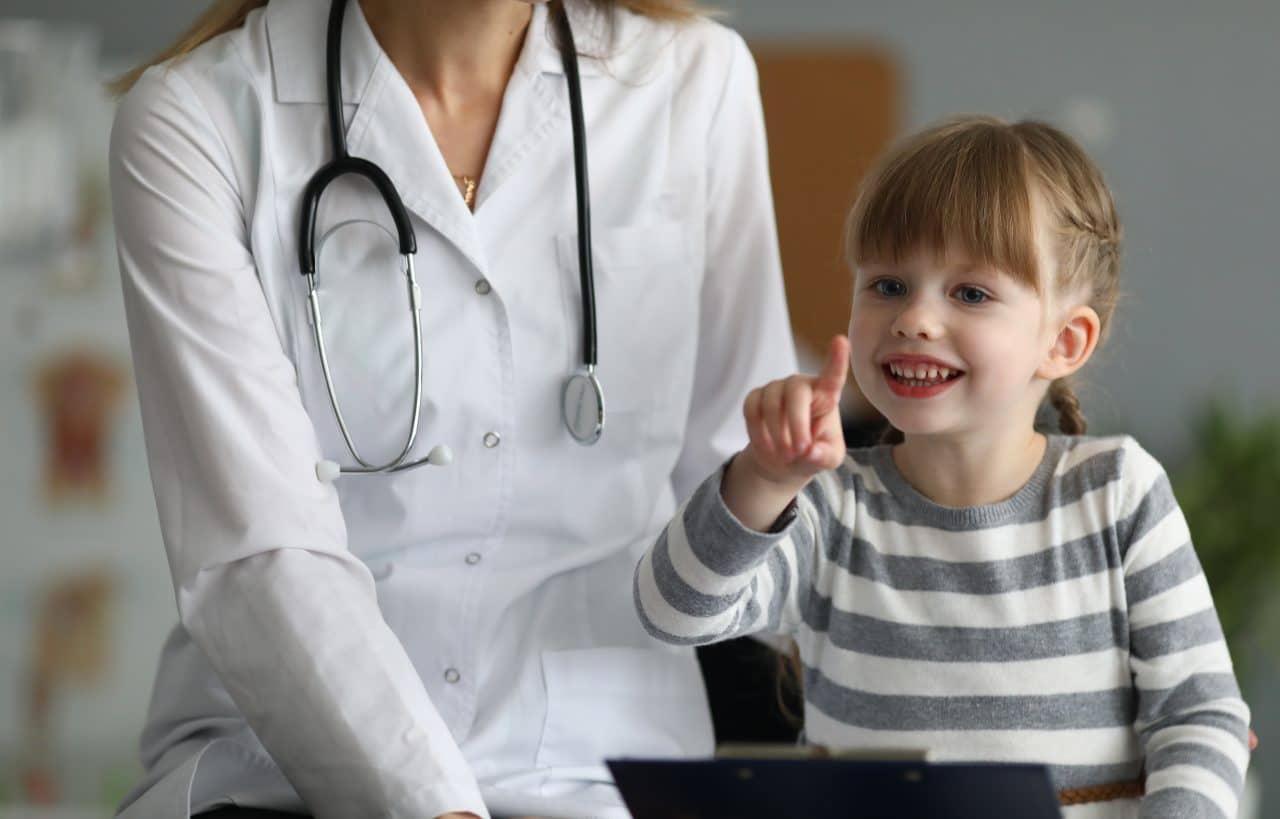 Close-up of smiling child pointing finger and holding paper folder.