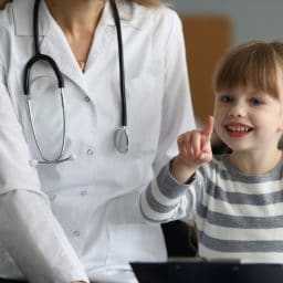 Close-up of smiling child pointing finger and holding paper folder.