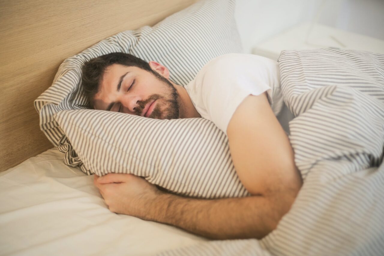 Man holding a pillow while sleeping in bed.