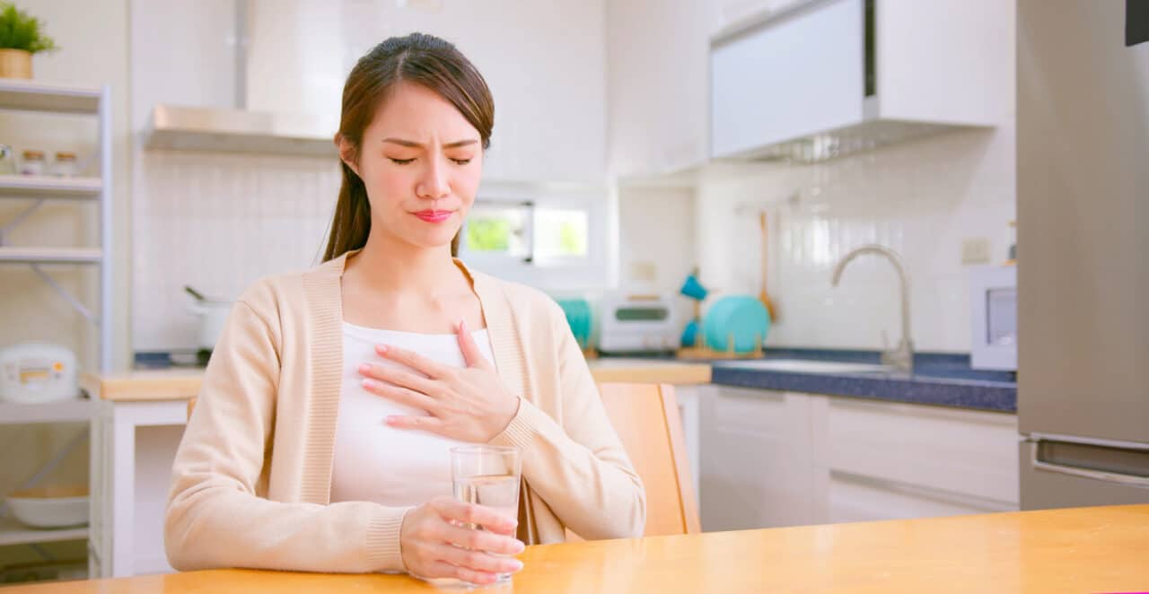 Woman with acid reflux putting her hand on her chest.