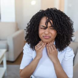 Young woman experiencing throat pain and tightness.
