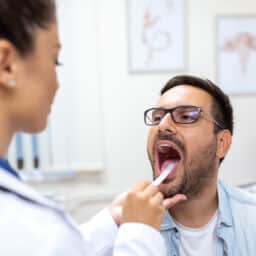 Doctor using a tongue depressor to check patient for strep throat