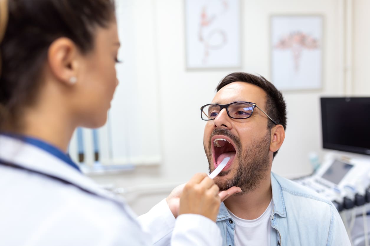 Doctor using a tongue depressor to check patient for strep throat 