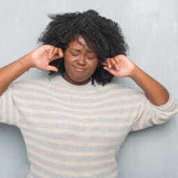 Woman plugging her ears to try and stop musical ear