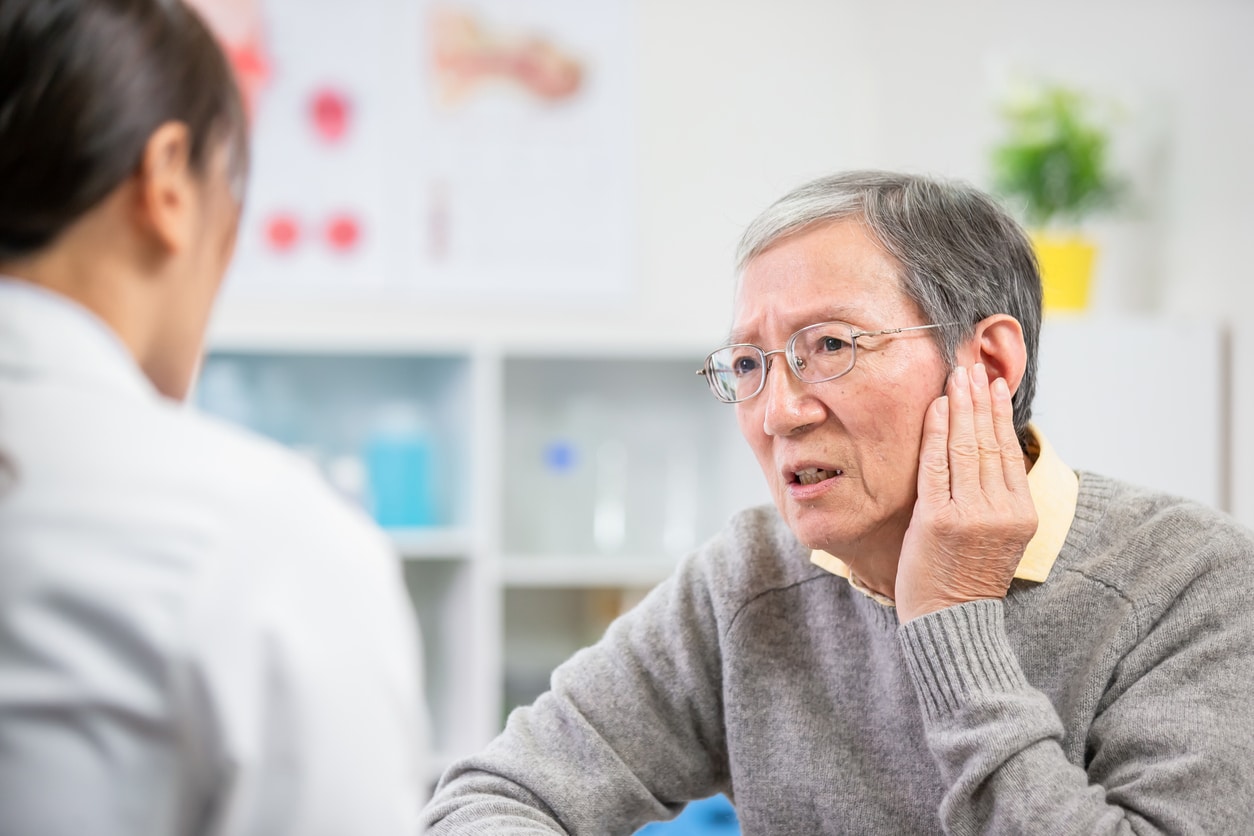 Man explaining ear pain to his ENT specialist.
