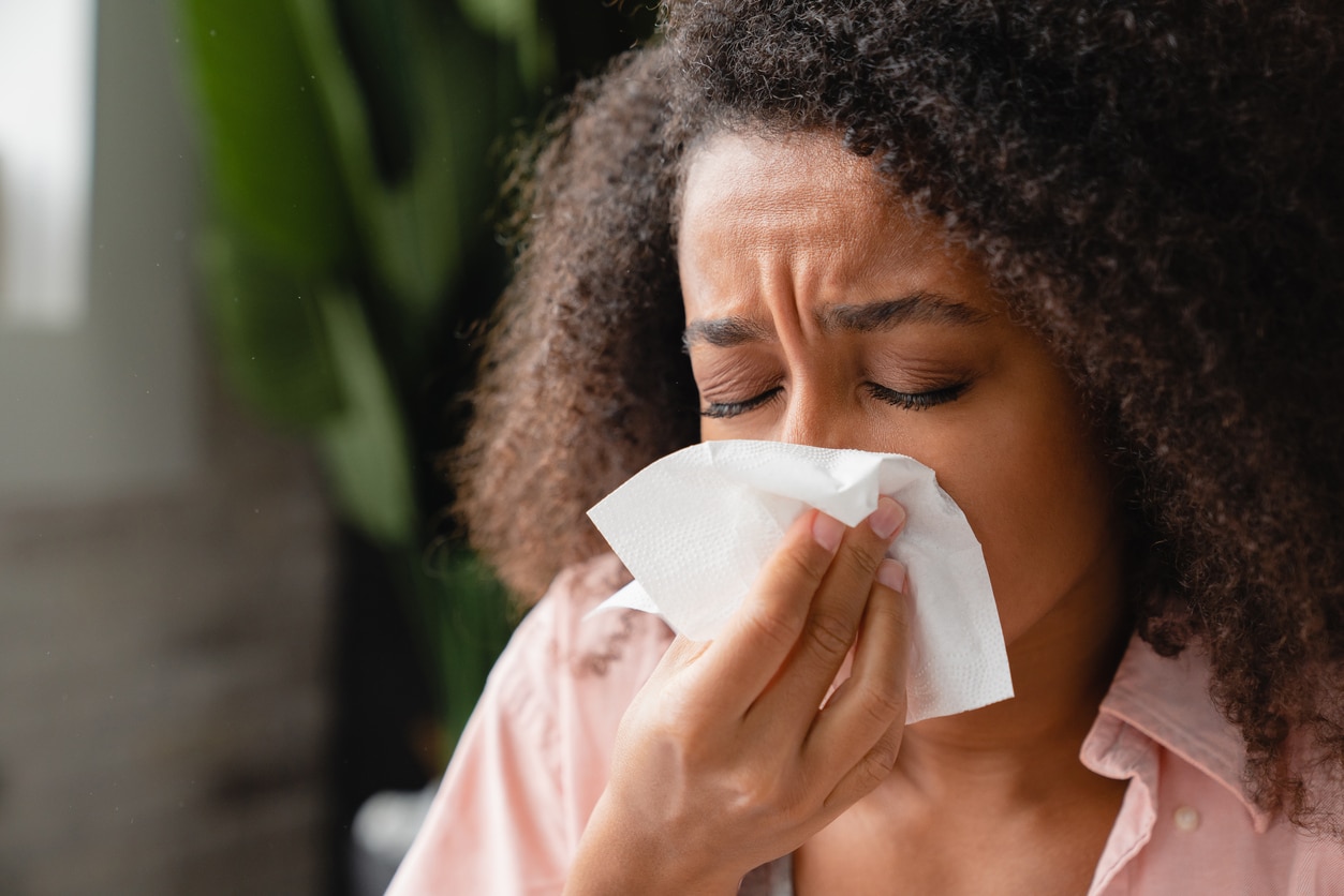 Woman sneezes into tissue
