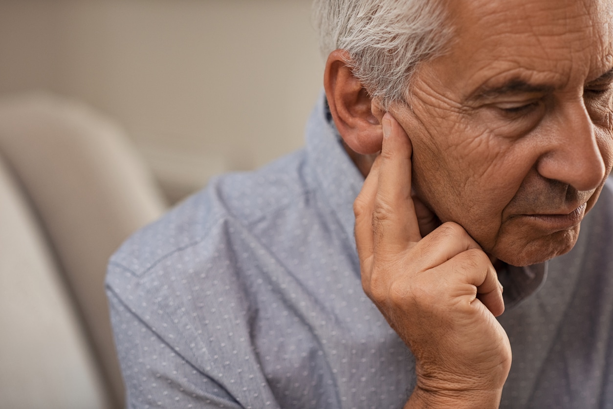 Man with ear pressure holds ear