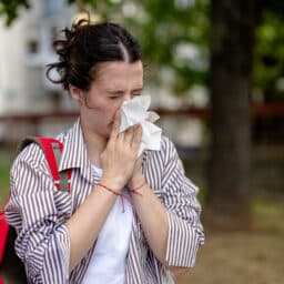 Woman outside blowing her nose
