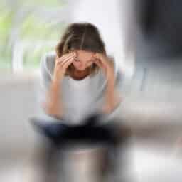 Woman with vertigo sitting down and holding her head