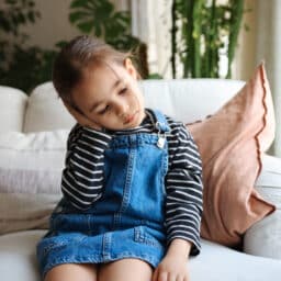 Young girl holds ear in pain