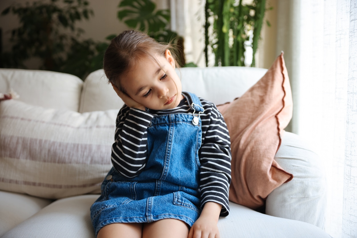 Young girl holds ear in pain