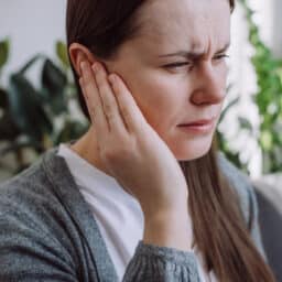 Woman with an ear infection holding her ear