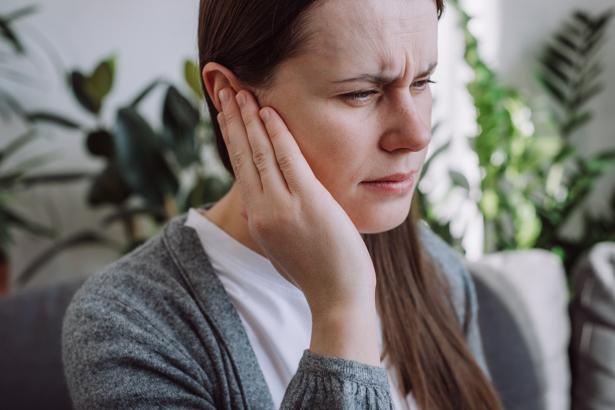 Woman with an ear infection holding her ear.