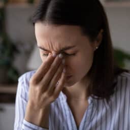 Woman with sinus pressure holding the bridge of her nose