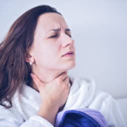 Woman holding her throat looking upset