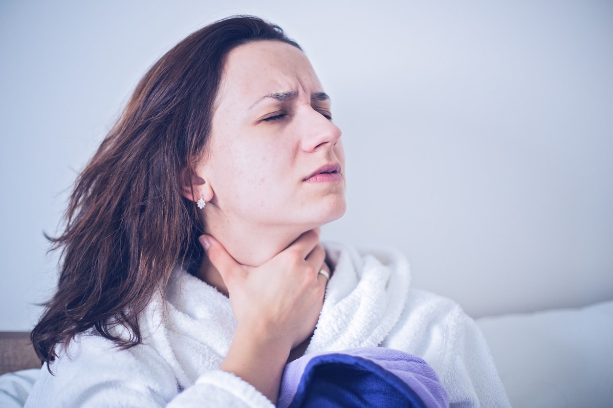 Woman holding her throat looking upset.