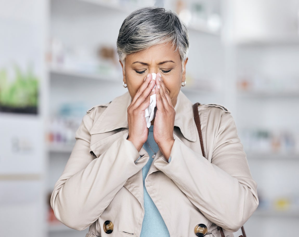 Woman blowing her nose into a tissue.