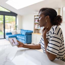 Woman at home talking to a doctor about her sore throat on a video call