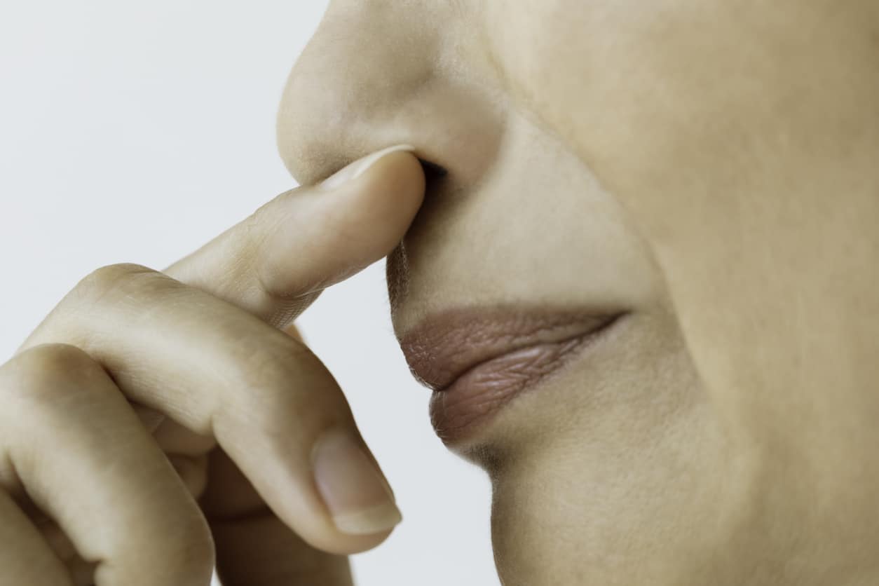 Woman holding her finger to her nose.