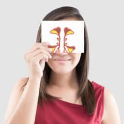 Woman holding up a card with a sinus illustration on it