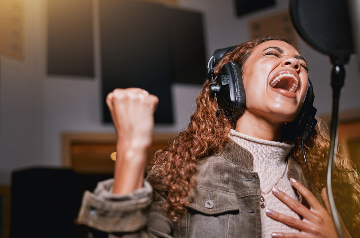 Young woman singing in a studio.