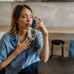 Young woman with asthma using her inhaler