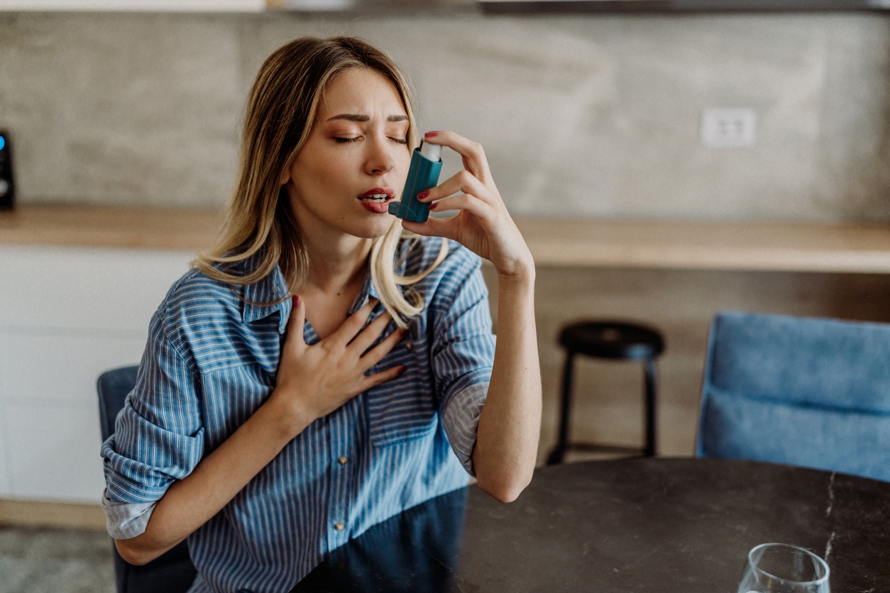 Young woman with asthma using her inhaler.