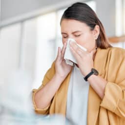 Woman blowing her nose at home