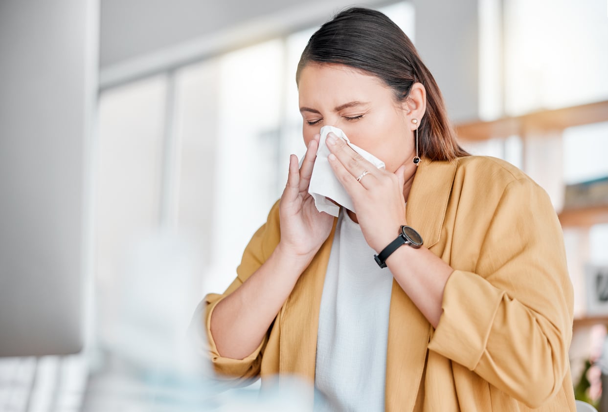 Woman blowing her nose at home.