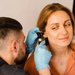 Otolaryngologist looks through otoscope the ears of woman