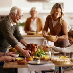 Happy senior man and his daughter serving Thanksgiving lunch to their family