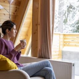 Woman with a hearing aid looking out a snowy window