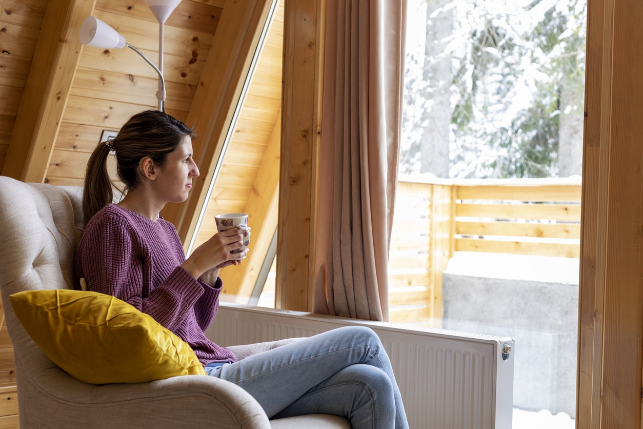 Woman with a hearing aid looking out a snowy window.